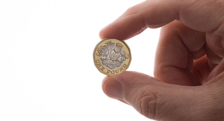 A hand holding up a 12-sided £1 coin.