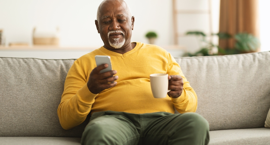 A man enjoying a cup of coffee and looking at his phone.