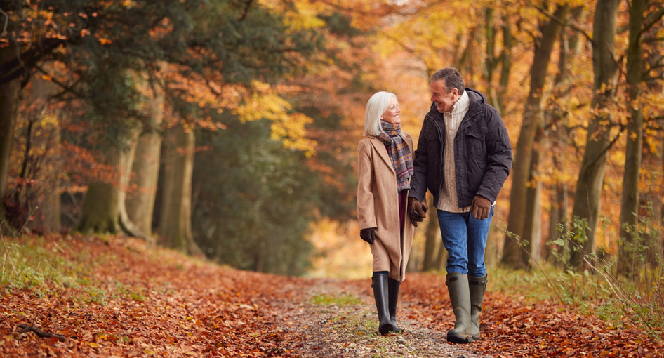 An older couple walking through woodland.