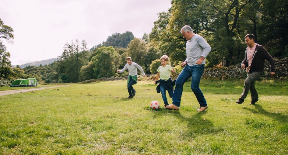 Multi-generational family playing football in a park.