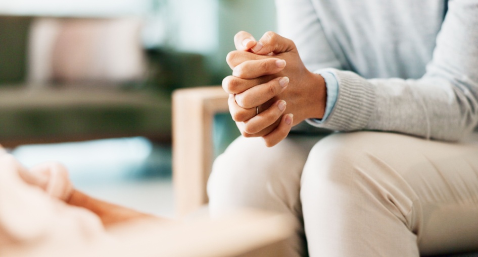 A woman sitting with her hands clasped.