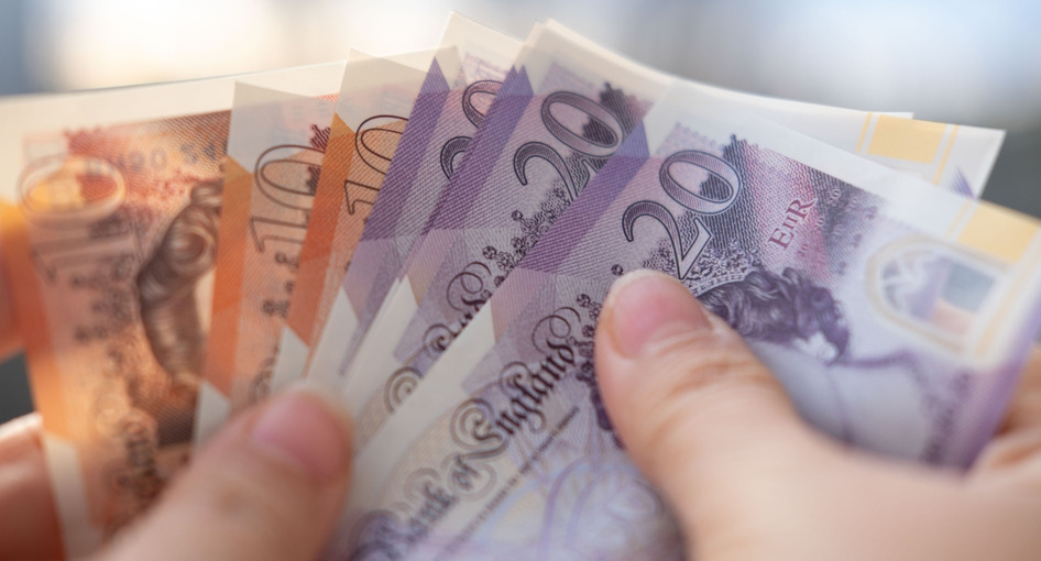 A person holding UK bank notes.